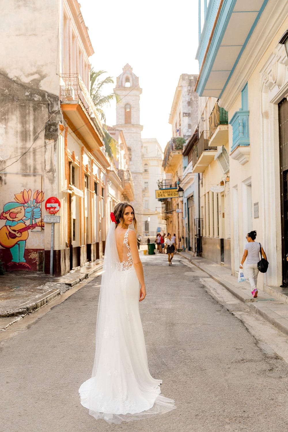 Model wearing Vinka Design Carmen Wedding Dress, a V Neck A-Line Wedding Gown worn on the streets of Havana with the dress flowing on the road