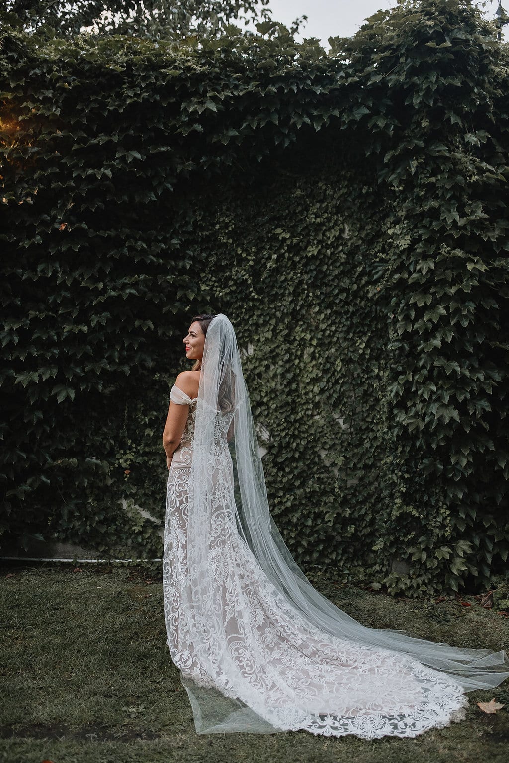 Real Weddings | Vinka Design | Real Brides Wearing Vinka Gowns | Amber and Rhys - Amber facing away with veil and off shoulder custom made dress and beautiful long train