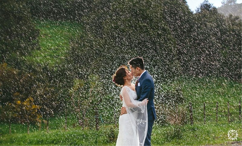 Testimonials | Vinka Design | Real Bridal Reviews from Our Clients | Belle and husband kissing with green hedge background