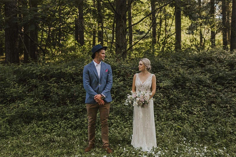 Testimonials | Vinka Design | Real Bridal Reviews from Our Clients | Briar and Corey outdoors in forest side by side showing beautiful v neck of gown detail