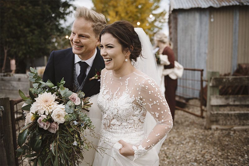 Testimonials | Vinka Design | Real Bridal Reviews from Our Clients | Catherine and husband smiling together with bridal designer gown highlighting beautiful lace detail on bodice