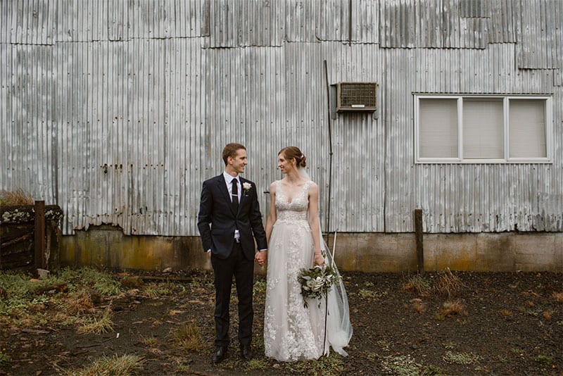 Testimonials | Vinka Design | Real Bridal Reviews from Our Clients | Melissa and Lachlan holding hands with lace front detail and v neck of beautiful bespoke gown featured