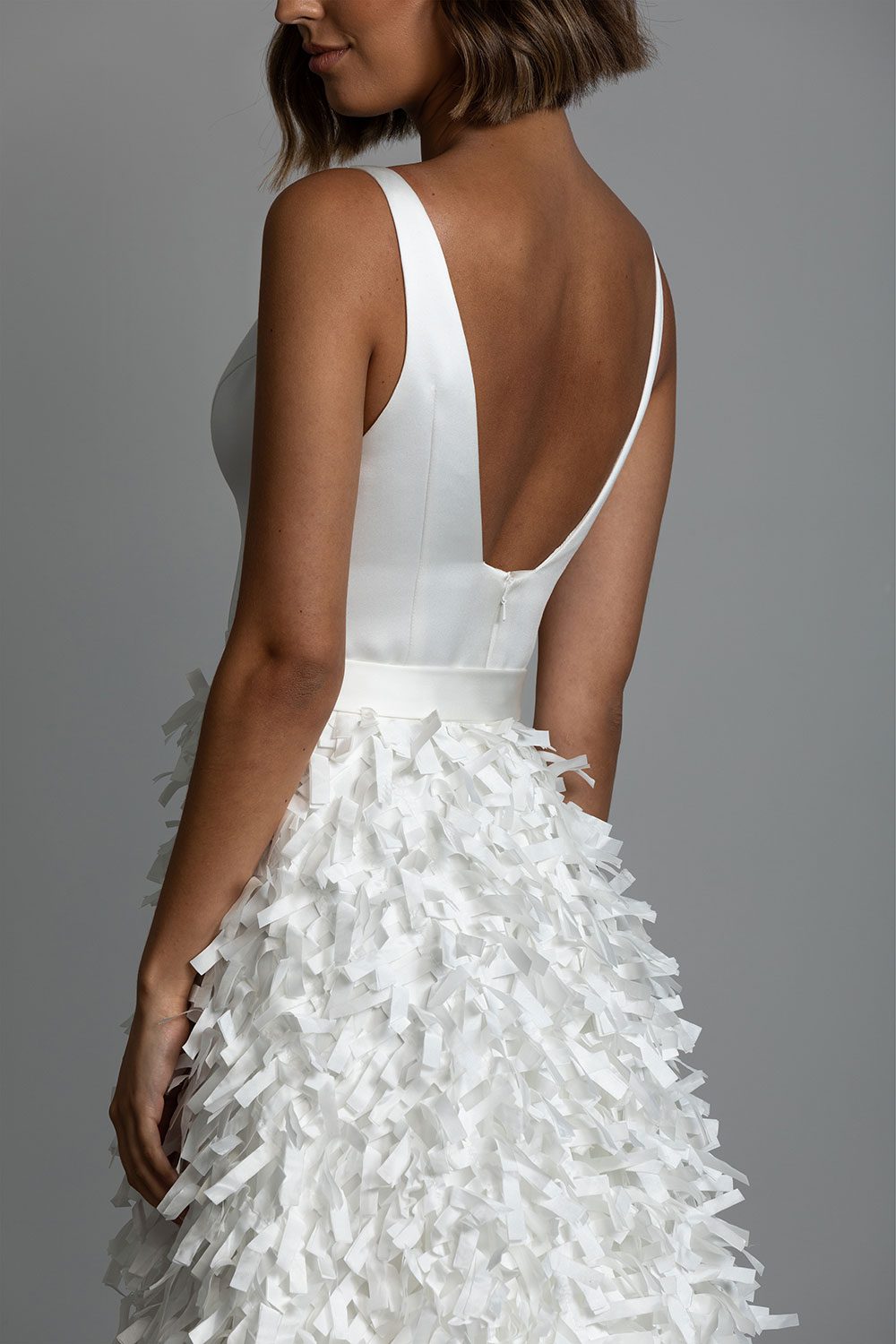 Bianca wedding dress from Vinka design. Close up view of squared back of the gown with satin belt and ribbon cut skirt