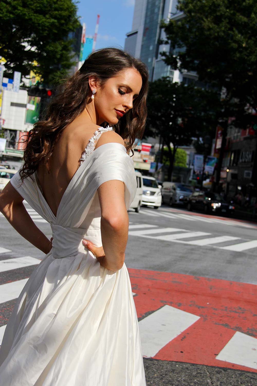 Female model wearing Vinka Design An Oriental Affair Wedding Dress. In a busy japanese crossing the back detail of a three-dimensional beaded flower lace gown on a nude base with a kimono over-dress and slim fitting floor length skirt.