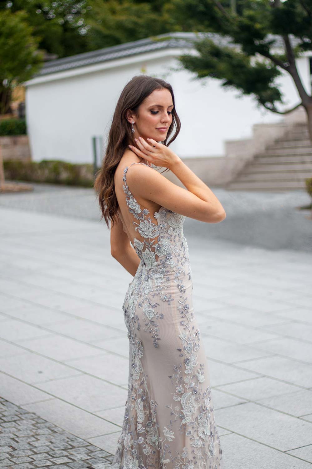 Female model wearing Vinka Design An Oriental Affair Wedding Dress. At a japanese temple in Kyoto the side detail of a slender silhouette form-fitting gown with a low sheer back, deep v-neckline and thin straps