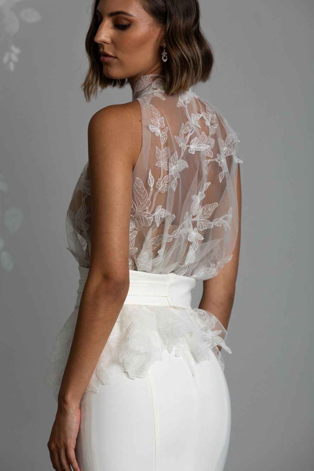 Mio Wedding Dress from Vinka Design. The front detail of gown with a high necked delicately hand-embroidered leaf lace cinched in at the waist with a wide kimono belt with skirt. Back view of dress with top with leaf lace embroidery and cinched waist with kimono belt