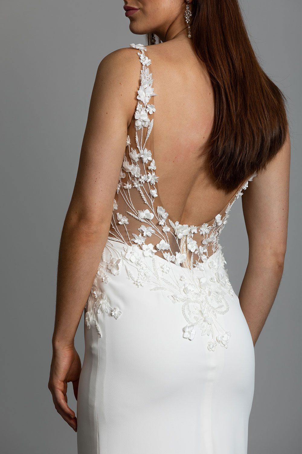 Reina Wedding Dress from Vinka Design. The front detail of a three-dimensional beaded flower lace gown on a nude base with a kimono over-dress and slim fitting floor length skirt. Close up of back of the dress with sheer illusion low back with 3D floral lace embroidery