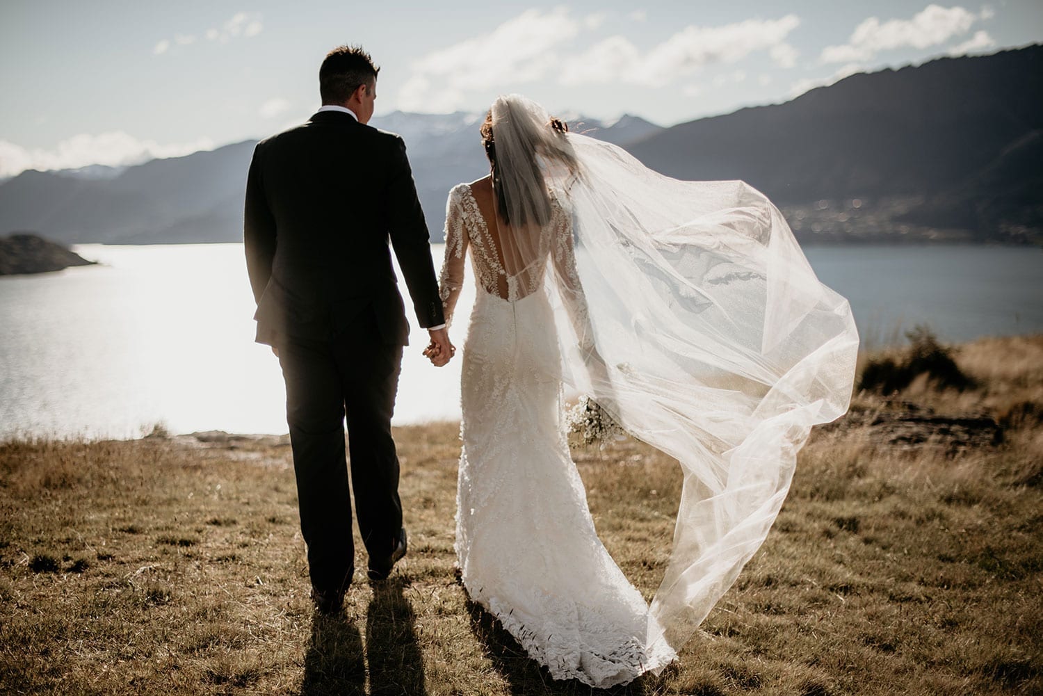 Vinka Design Features Real Weddings - Bride in custom made gown with groom looking out to lake in remarkables mountains