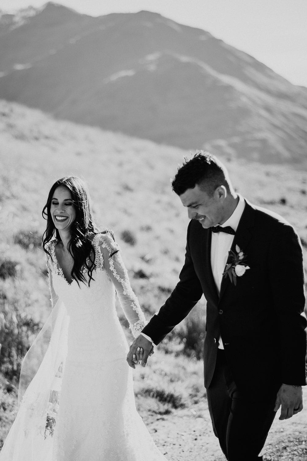 Vinka Design Features Real Weddings - Bride in custom made gown walking along pathway with remarkables mountains backdrop in black and white