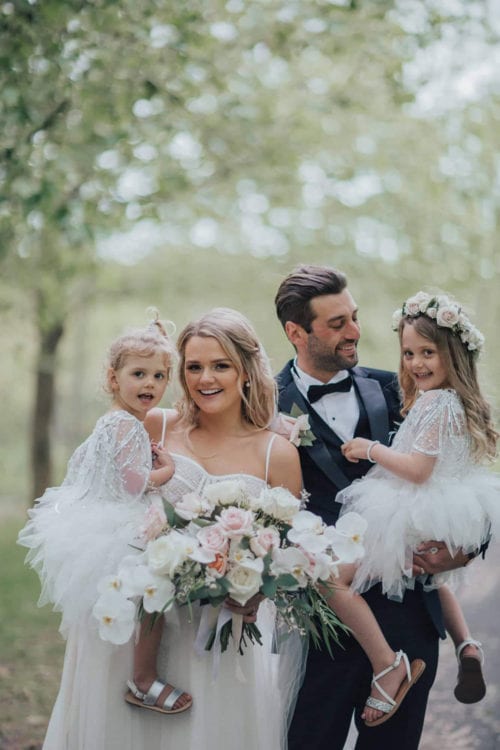 Vinka Design Features Real Weddings - bride wearing custom made gown with two different beadings incorporated into a fitted, structured bodice, and dreamy layered tulle skirt. Bride and groom with children in blossom trees