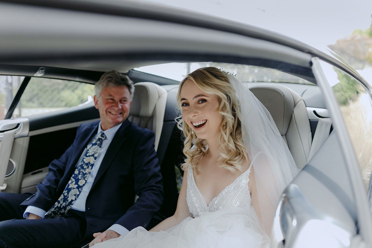 Vinka Design Features Real Weddings - bride in custom made Keiko gown from the Oriental affair collection with additional delicate dimensional flower lace added to the bodice and beading added to the skirt layers. Bride arriving in car