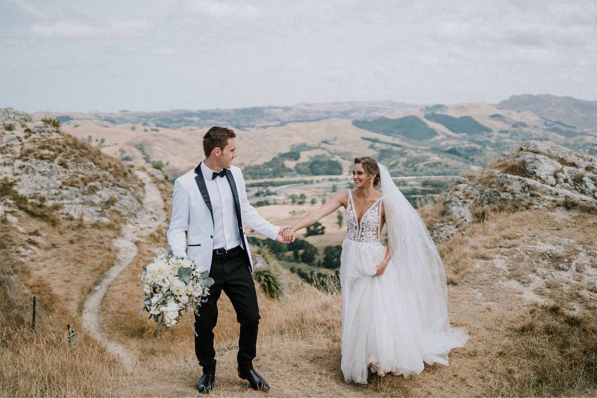 Vinka Design Features Real Weddings - bride in custom made gown. Bride and groom hand in and on mountain