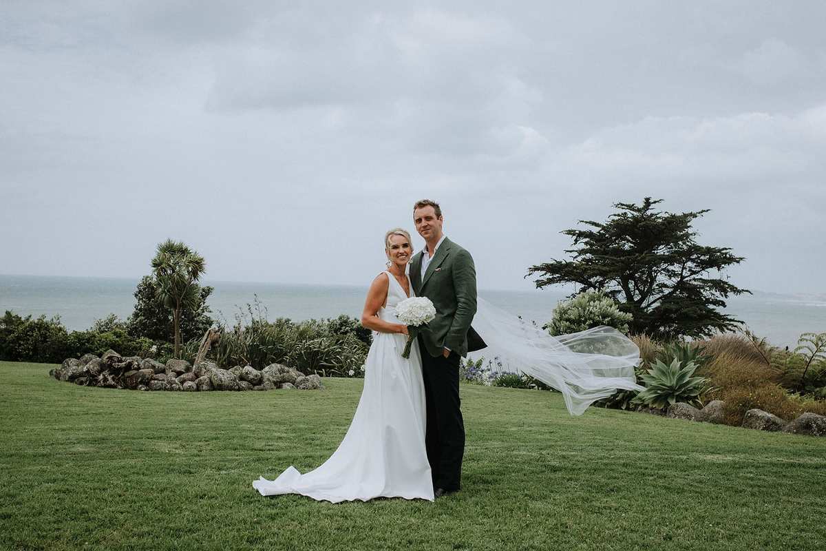 Vinka Design Features Real Weddings - bride in custom made gown. Bride and groom outdoors with ocean in the background