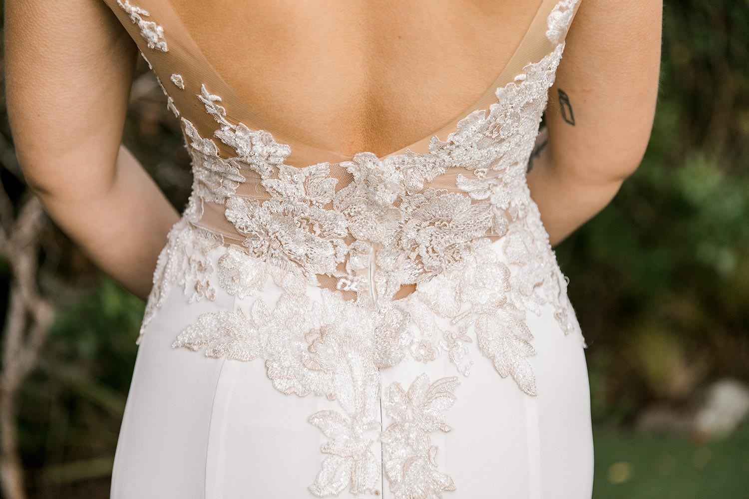 Samantha Wedding Dress from Vinka Design. This beautiful wedding dress has a nude sheer illusion strapless neckline made from fine Italian tulle. Low sheer back & structured bodice, & soft crepe train. Close up detail of low back. Photographed in Landscaped garden.