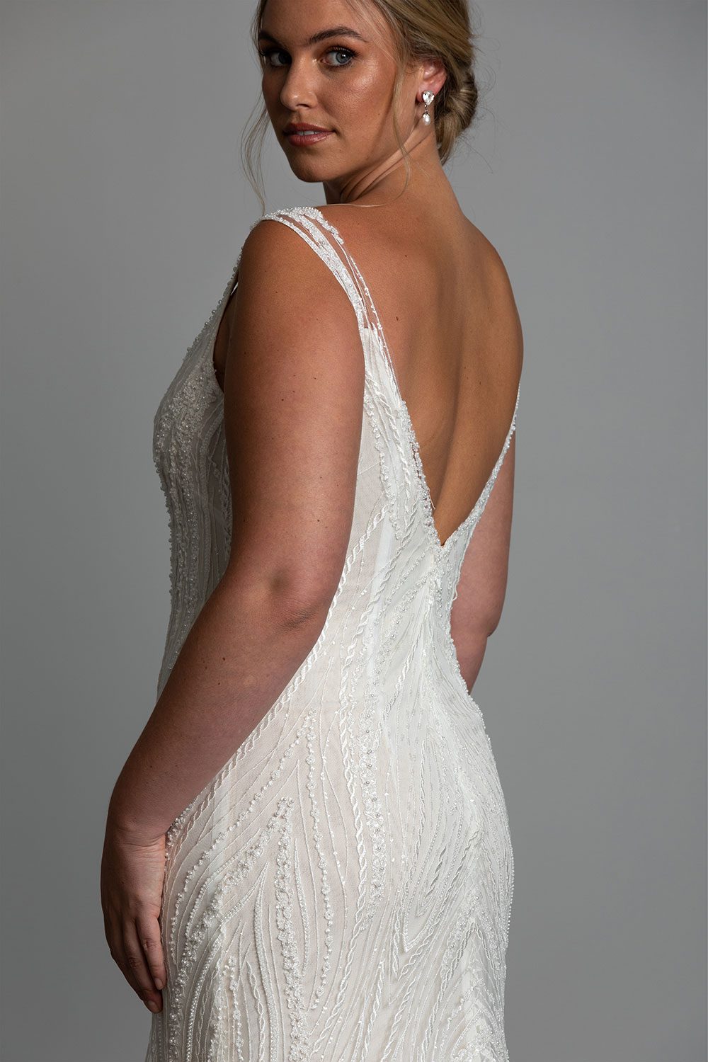 Kiera Wedding Dress from Vinka Design. Beautifully beaded lace wedding dress. Deep V-neckline both front and back is complemented with delicate sheer lace shoulder detail & structured bodice. Close up of deep V back with boing and beaded lace