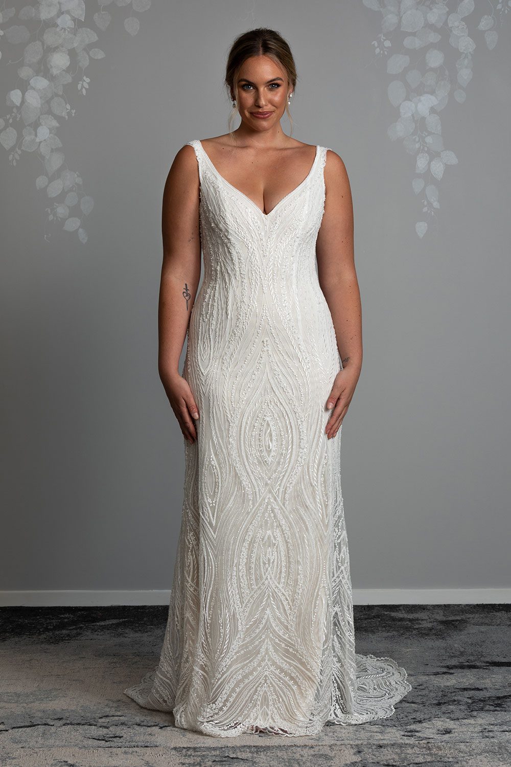 Kiera Wedding Dress from Vinka Design. Beautifully beaded lace wedding dress. Deep V-neckline both front and back is complemented with delicate sheer lace shoulder detail & structured bodice. Full length view of gown with deep V-neckline and delicate beaded lace