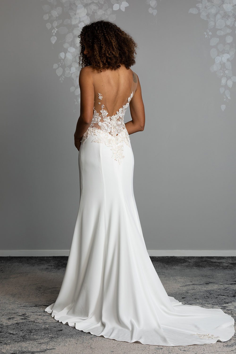 Samantha Wedding Dress from Vinka Design. This beautiful wedding dress has a nude sheer illusion strapless neckline made from fine Italian tulle. Low sheer back & structured bodice, & soft crepe train. Model showing full length back view of dress with low sheer back and bridal crepe train