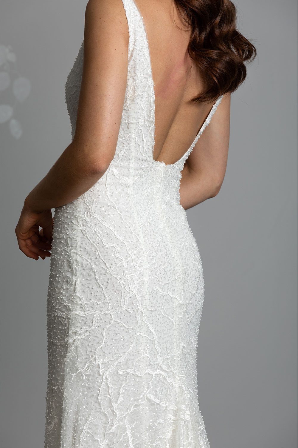 Farrah Wedding gown from Vinka Design - This beautiful wedding dress is constructed with fully beaded embroidered lace on a stretch base. V-neckline with a low, square back cut in a fit-and-flare style, which gently sculpts and enhances curves. Close up of low square cut back