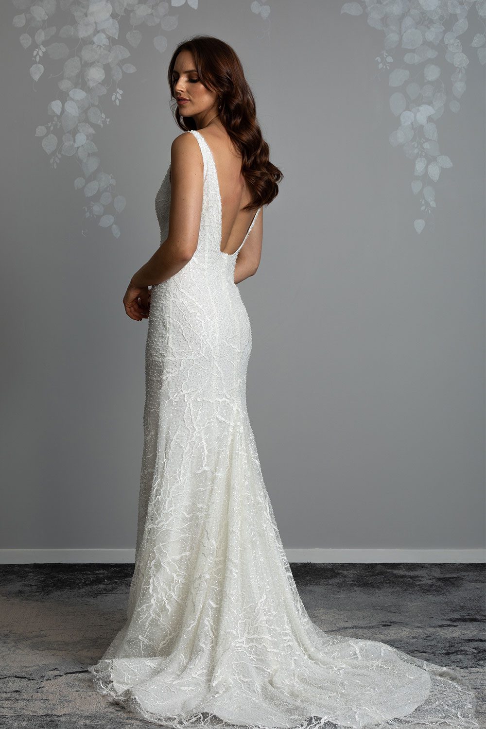 Farrah Wedding gown from Vinka Design - This beautiful wedding dress is constructed with fully beaded embroidered lace on a stretch base. V-neckline with a low, square back cut in a fit-and-flare style, which gently sculpts and enhances curves. Full length view of back of dress with square cut low back detail and long train