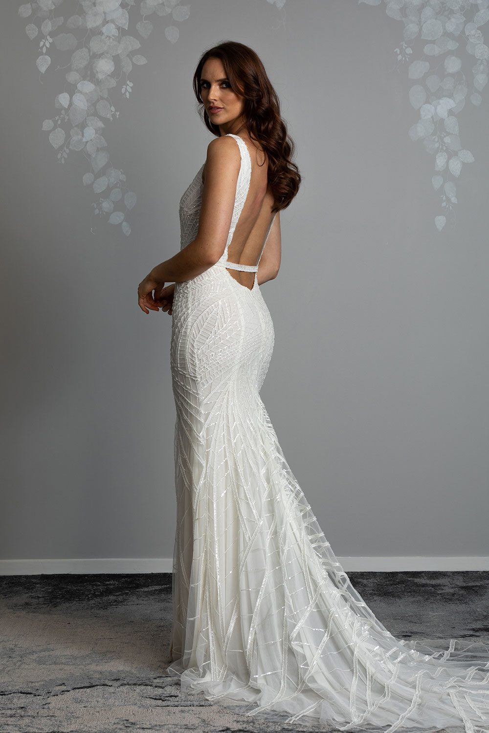 Elle Wedding gown from Vinka Design - Wedding dress with illusion neckline and deep plunge in the front with low back. Stunning beaded embroidery over a stretch base that sculpts and flatters the figure and falls into a beautiful flared train. Full length view of back of dress showing the beautiful flared train and low cut back