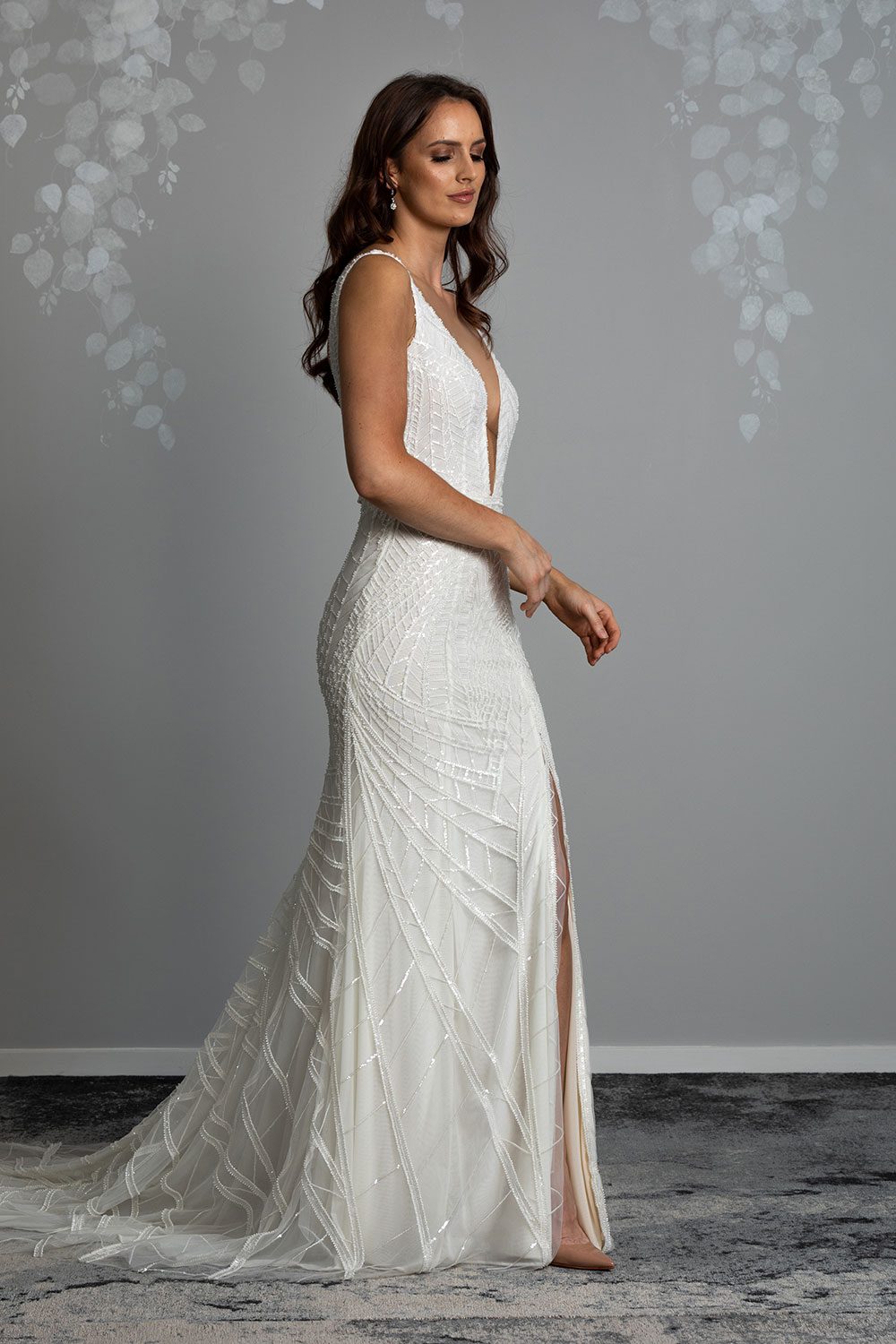 Elle Wedding gown from Vinka Design - Wedding dress with illusion neckline and deep plunge in the front with low back. Stunning beaded embroidery over a stretch base that sculpts and flatters the figure and falls into a beautiful flared train. Profile view of dress with deep plunge neckline and optional side split