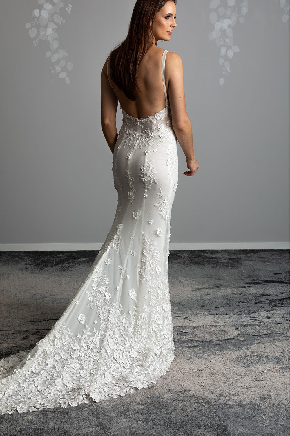 E'more Wedding gown from Vinka Design - This stunning lace wedding gown is hand sewn with a fully beaded 3D flower embroidery. Structured and boned bodice with scoop neckline in the front and low back. Stretch fit skirt flares into full lace train. Full length view of back of the dress with low back and long lace train