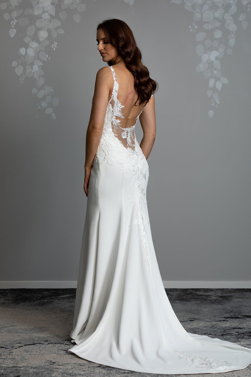Ana Wedding gown from Vinka Design - This beautiful gown is graced by hand-appliqued delicate floral leaf lace, subtly worked into the front of the bodice and more prominently on the back. A fit-and-flare cut shapes the figure. Model showing side profile of low back with stunning lace on illusion tulle