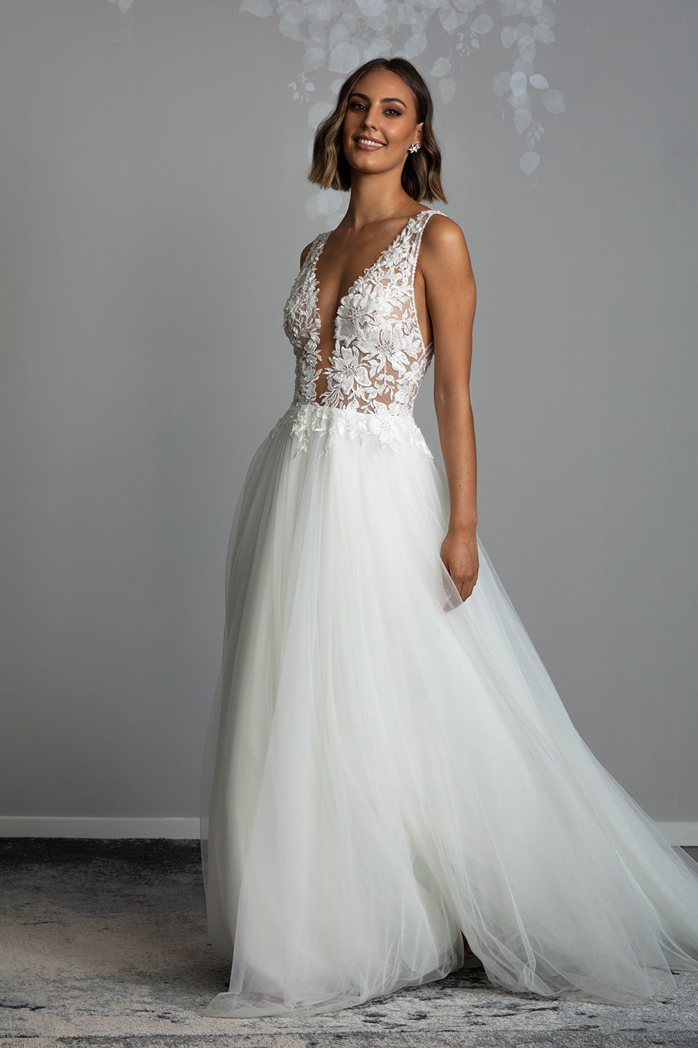Tia Wedding gown from Vinka Design - This dreamy sculpted wedding dress has a deep V-shaped illusion neckline with beaded floral lace and an open back. The skirt has layers of soft tulle that glide with movement. Model walking showing movement in the soft tulle skirt