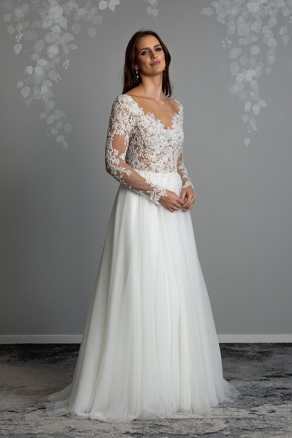 Maia Wedding gown from Vinka Design - This feminine & romantic wedding dress features beautiful pearl & bead embroidery over 3D lace. Long sleeves with pearl buttons, illusion neckline and skirt of dreamy layers of soft tulle. Full length view of romantic dress with beautiful long lace sleeves and flowing tulle skirt