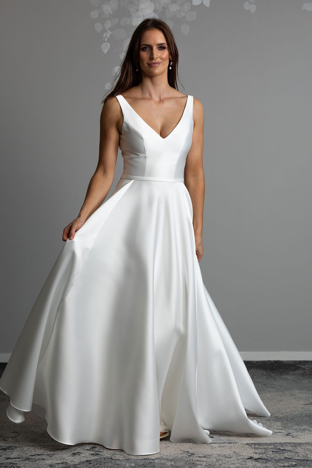 Madison Wedding gown from Vinka Design - This gown is both classic and contemporary, made beautifully with luxurious Mikado satin. The bodice is structured with a deep V-neckline and a squared, low back. Model showing the fullness of the skirt with irregular folds and fun and versatile side pockets