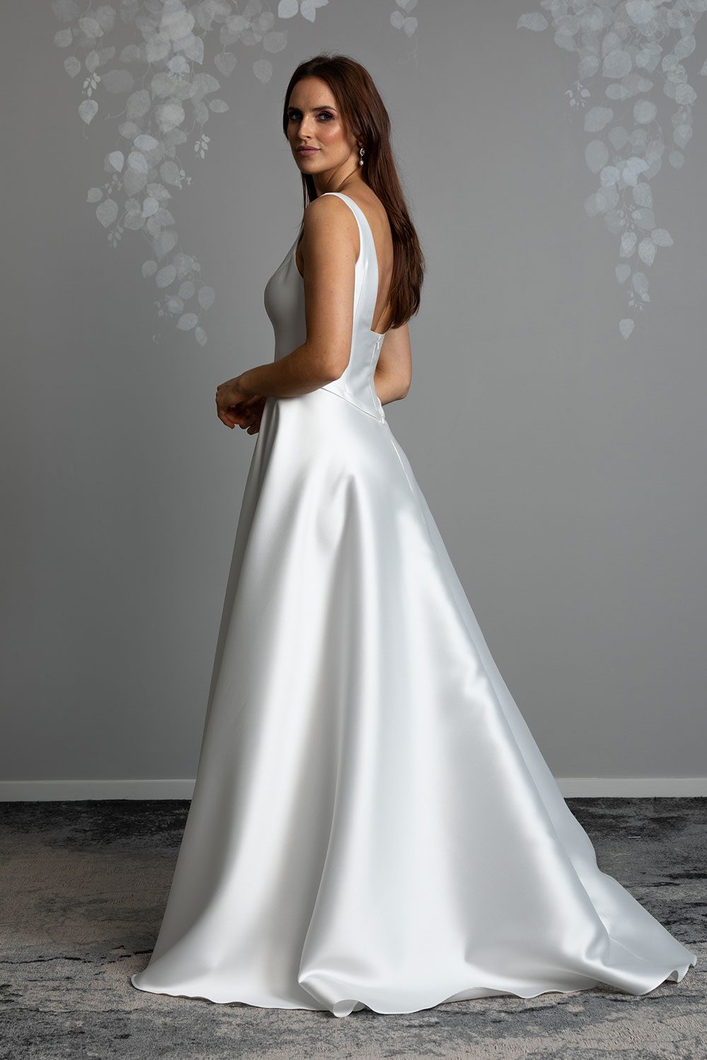 Madison Wedding gown from Vinka Design - This gown is both classic and contemporary, made beautifully with luxurious Mikado satin. The bodice is structured with a deep V-neckline and a squared, low back. Model showing profile view of gown with beautiful Mikado satin and the low square cut back with full skirt with elegant sweeping train