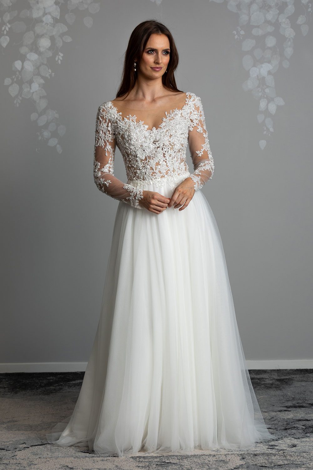 Maia Wedding gown from Vinka Design - This feminine & romantic wedding dress features beautiful pearl & bead embroidery over 3D lace. Long sleeves with pearl buttons, illusion neckline and skirt of dreamy layers of soft tulle. Full length view of the front of the gown displaying the delicate lace and embroidery on the bodice with long tulle skirt