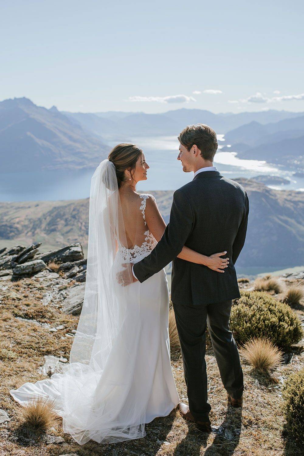 Bride wearing bespoke bridal gown with richly beaded lace over sheer tulle bodice and low back from Auckland wedding dress designer Vinka designs - back embrace with groom