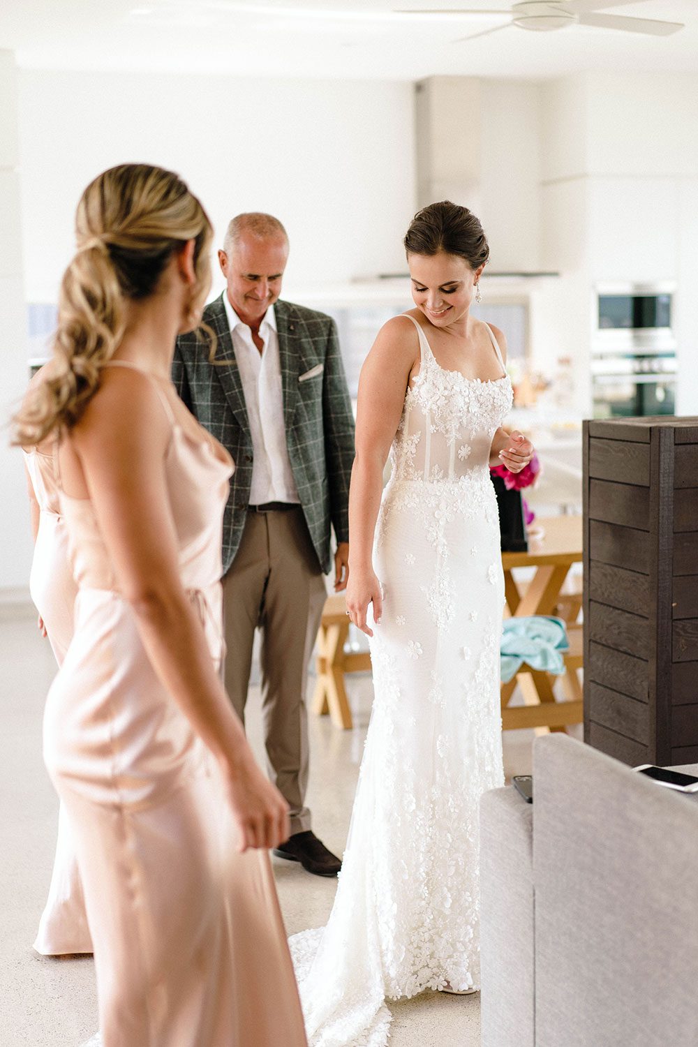 Bride wears bespoke E'More lace gown with boned bodice with hand beaded flower applique and full lace train by Auckland wedding dress maker Vinka designs - getting ready with bridesmaid and family