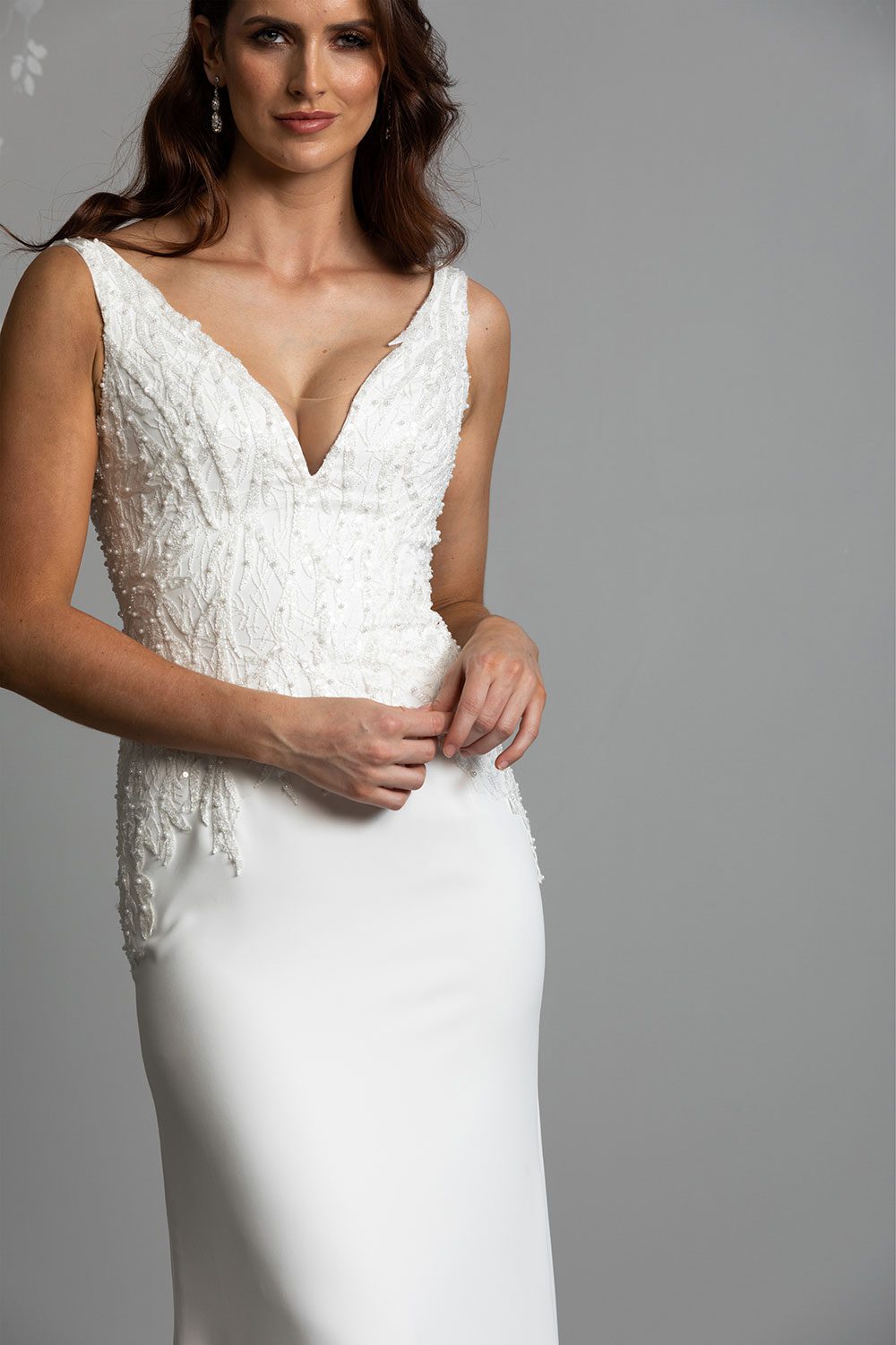Gene Wedding Dress by Vinka Design - Crafted in a luxe matte bridal crepe with beautiful hand-appliqued, beaded lace adorned with delicate seed pearls and dazzling iridescent sequins that shimmer with movement. The bodice is styled with a plunging V-neckline and a complementary V-back.