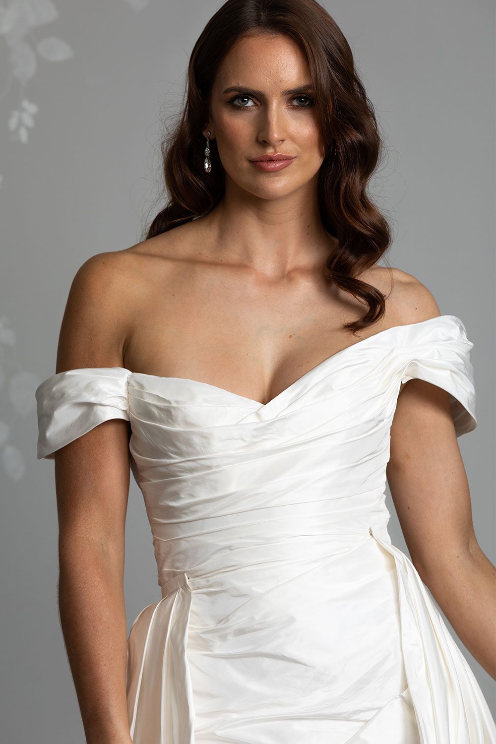 Marcella Wedding Dress by Vinka Design - An indulgent bridal gown of pure opulence. Marcella's statement look is emphasised through dramatic, draped folds of crisp Italian silk taffeta and delicate off shoulder detailing. The base gown features a sculptural fit-and-flare silhouette which fans into a small, elegant train. Close up view of off shoulder silk taffeta gown with draped detailing