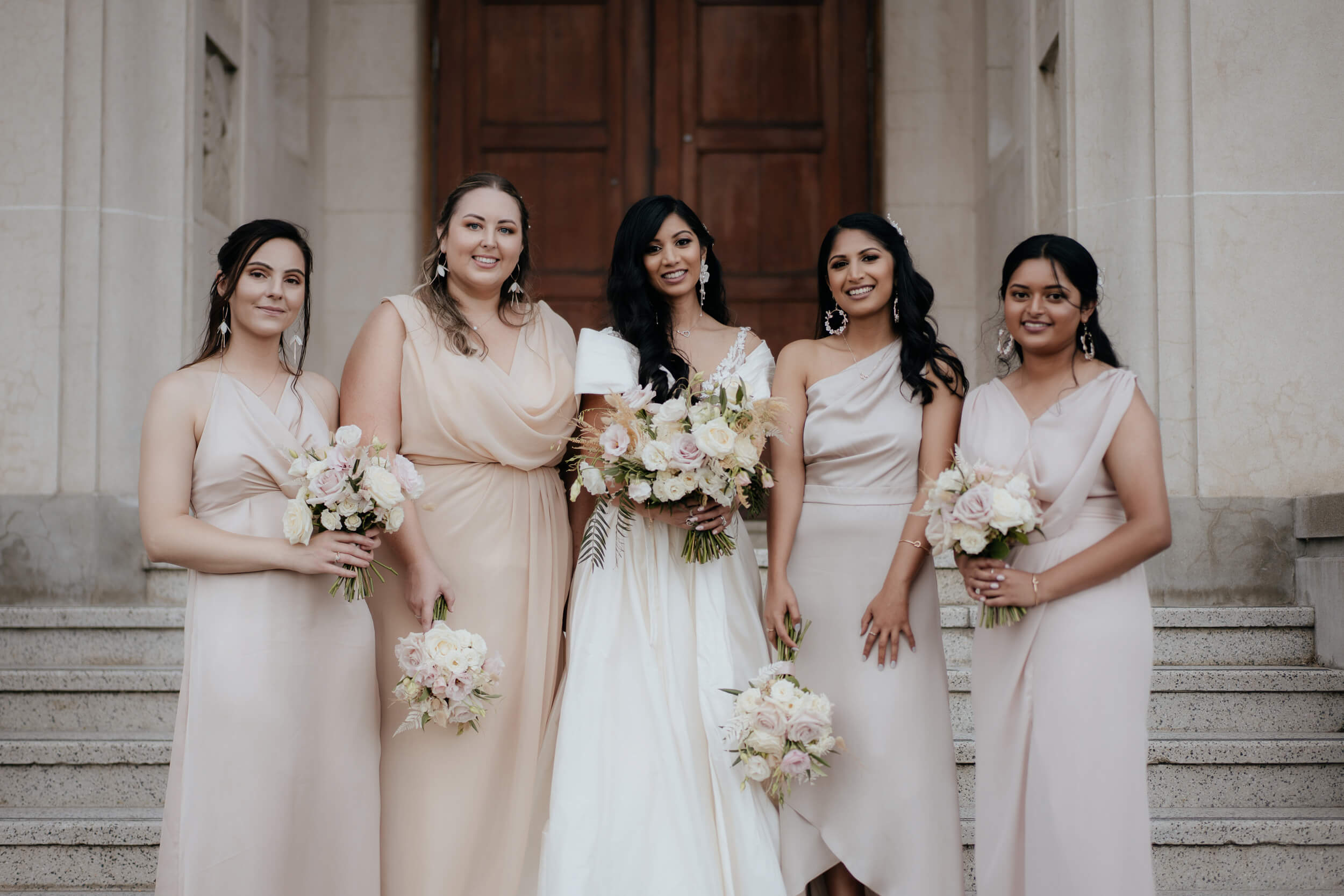 Vinka Design Real Wedding with Vinka Bride Prianka in full length wedding dress - bride poses with bridesmaids