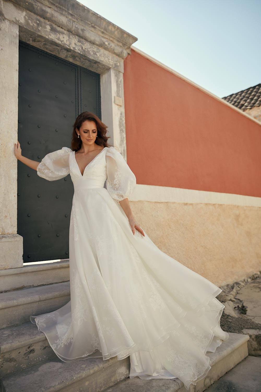 Discover Wedding Gown Bianca's blend of boldness and fragility. Features a plunging V-neckline, basque waist, sweeping silk organza train & detachable sleeves.