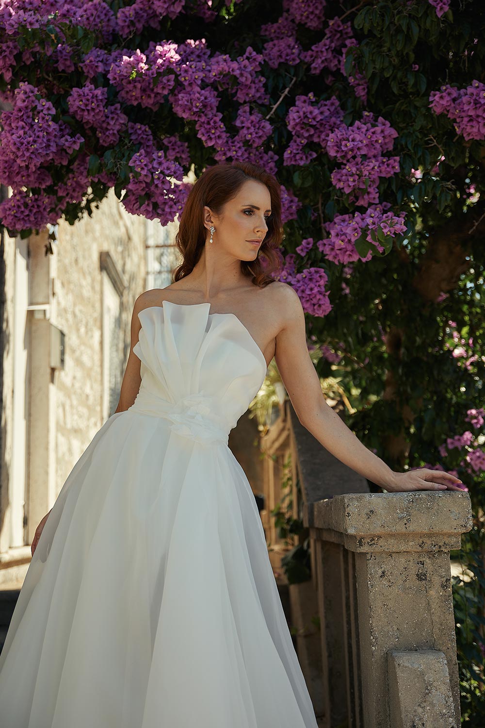 Rosana - bridal gown that embodies timeless elegance. Features satin organza, a strapless bodice, sweeping train, and hand-crafted rosette. On steps in Croatia